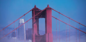 Golden Gate Bridge tower rising through fog with San Francisco skyline behind—scenic stop on a Teams & Groups food tour in SF.